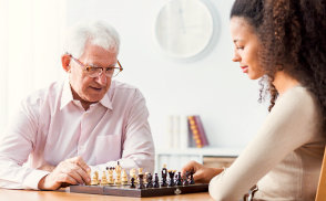 senior man and a caregiver playing board game